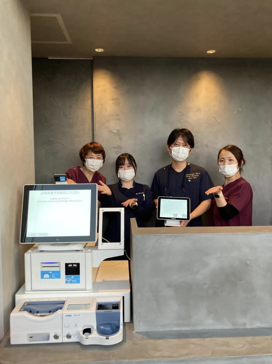 湯野歯科口腔外科クリニックの受付カウンターに設置された PLUM REGI とスタッフの皆さま